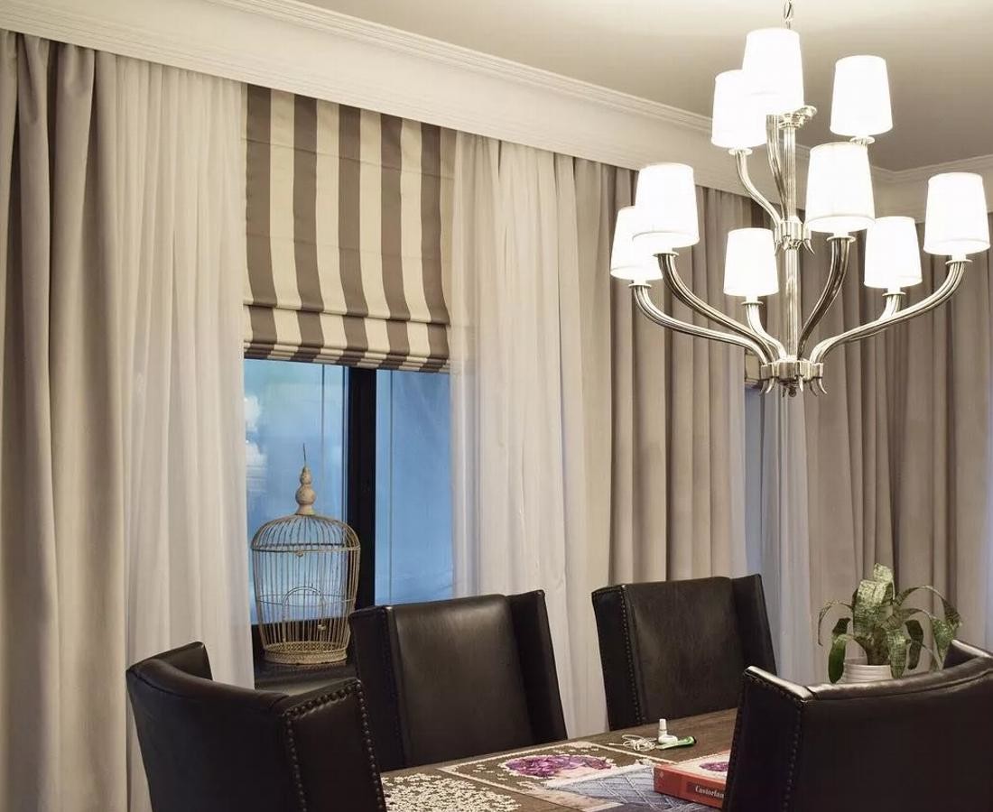 Римские шторы с электроприводом, выполненные в классическом дизайне, дополняют интерьер гостиной. Привод позволяет регулировать высоту штор с помощью дистанционного управления, что облегчает регулировку освещения и уровня приватности в комнате.